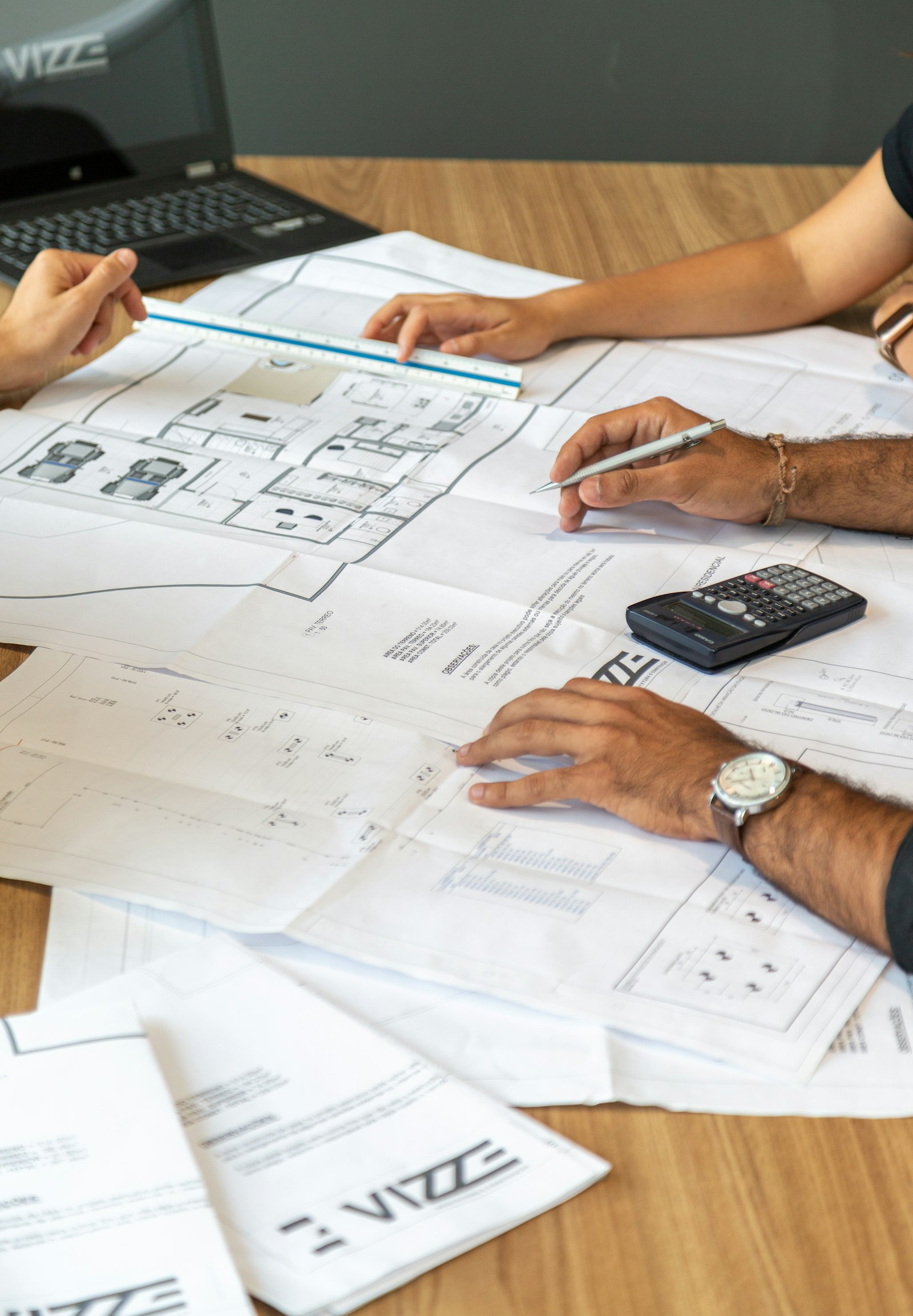 Architectural blueprints and rolled drawings spread across a working desk.