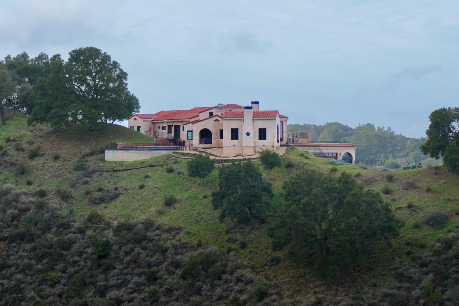 Small residence sited on a green hillside, low afternoon light along the roofline.