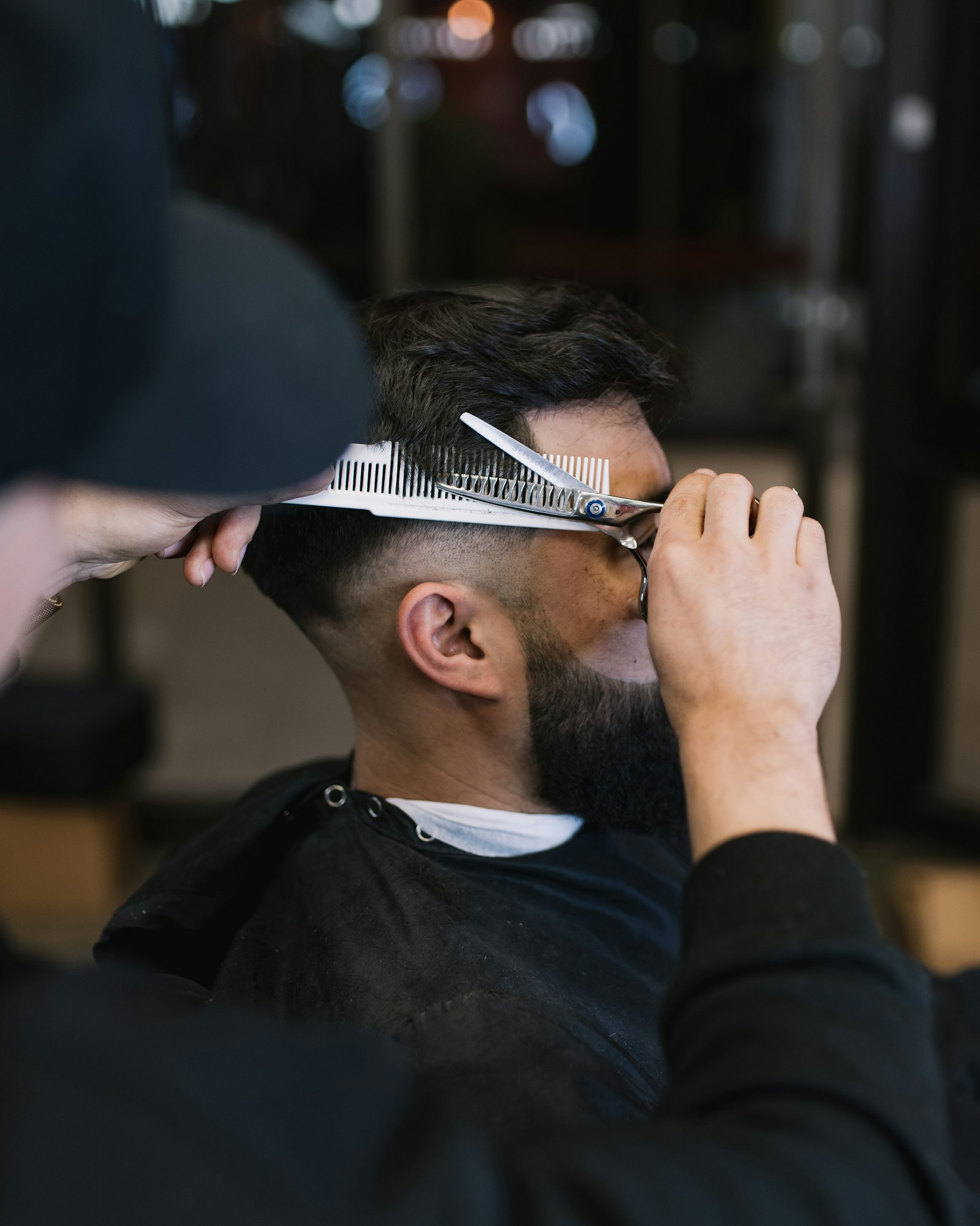 An instructor demonstrating a scissor-over-comb cut during a classroom practical.