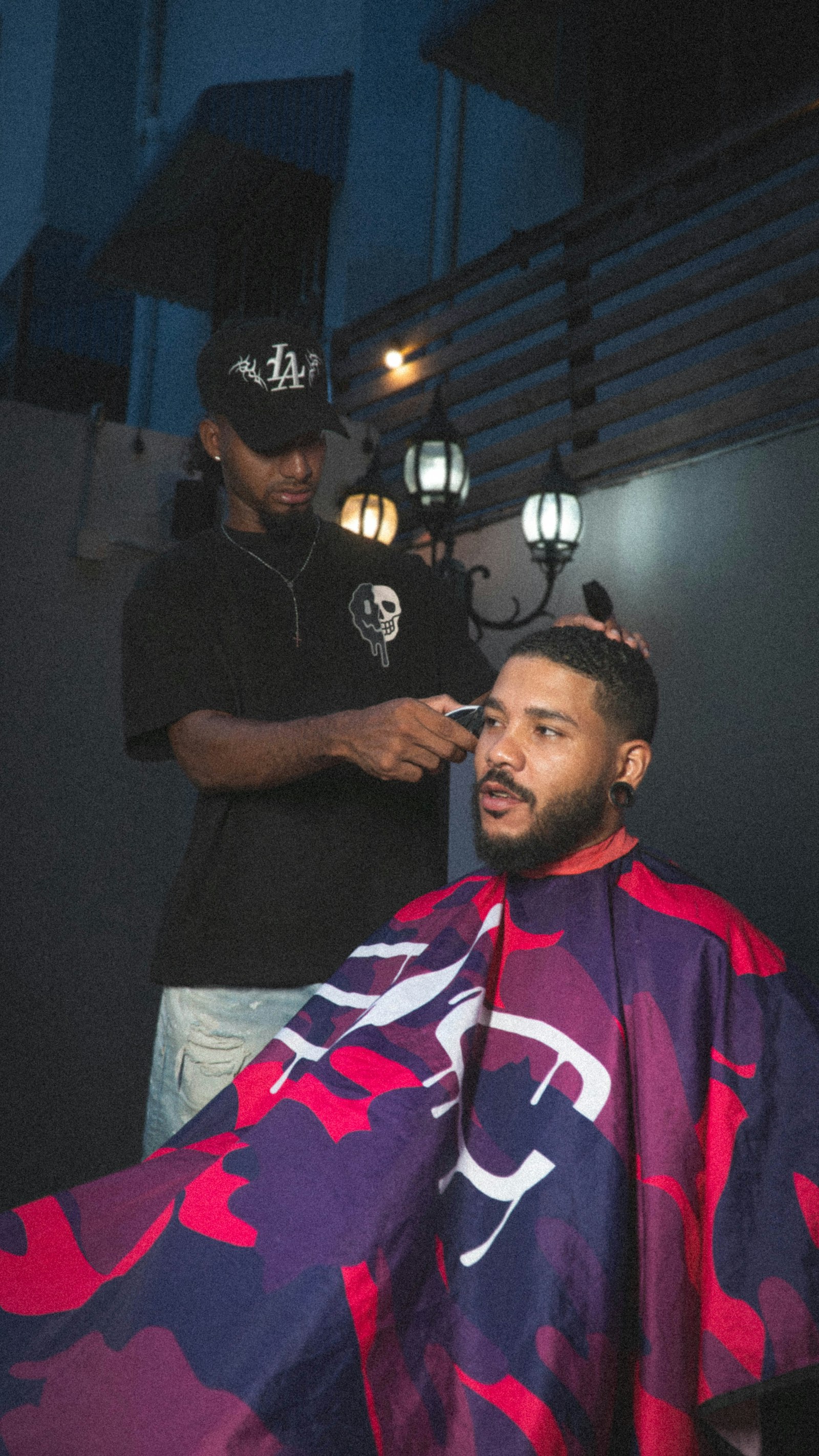A barbering student working a fade with clippers at the chair.