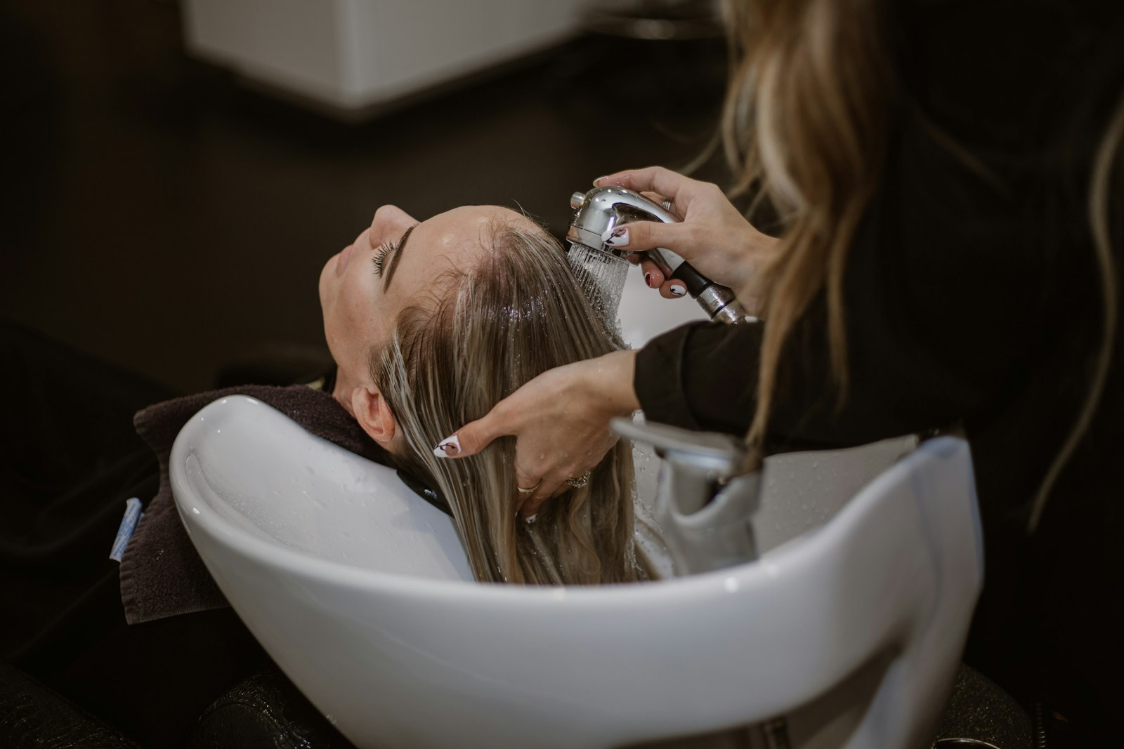A student stylist cutting a client's hair during cosmetology clinical hours.