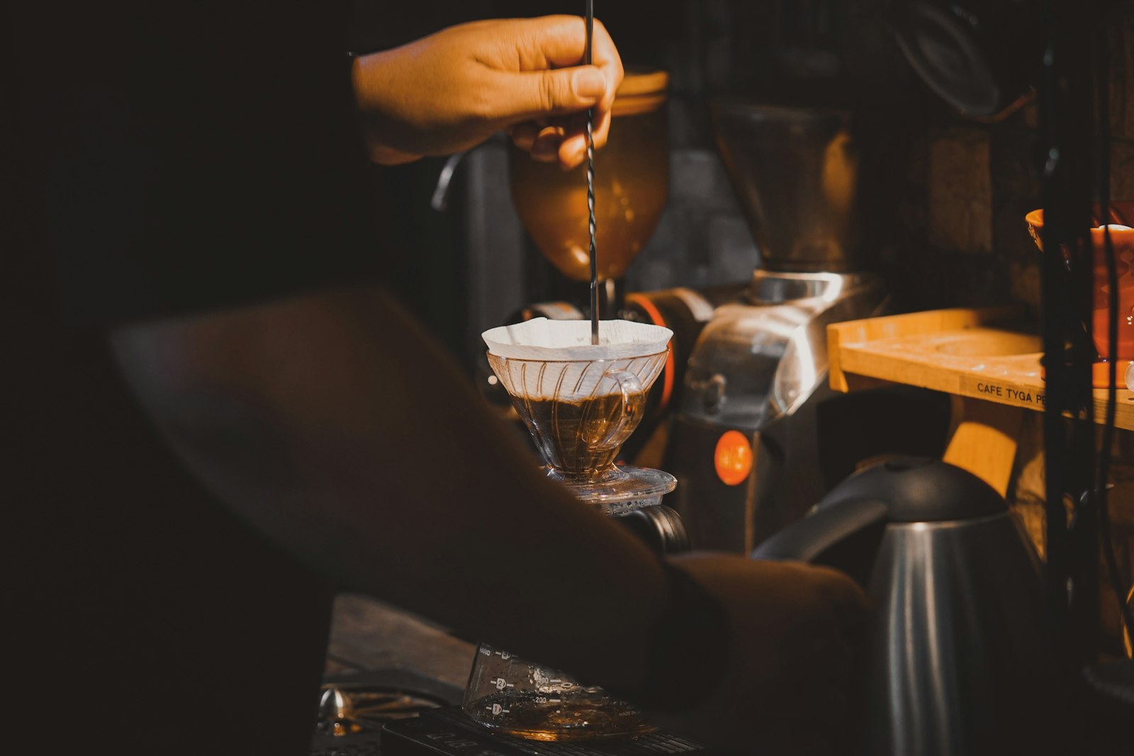 A hand pouring water from a gooseneck kettle over a pour-over filter cone