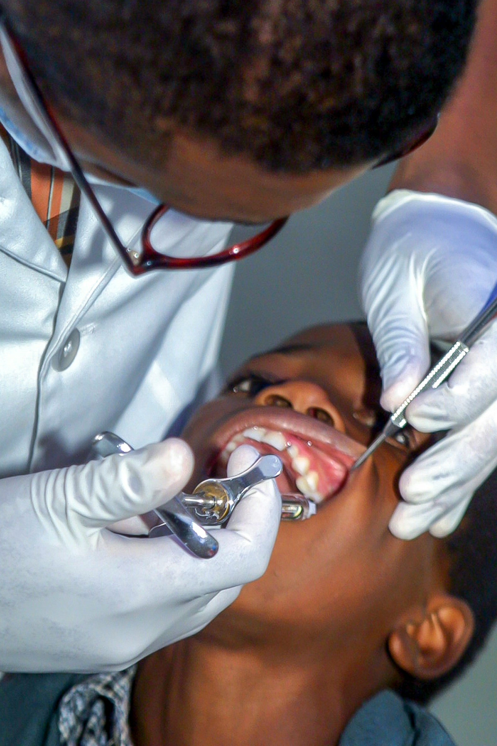 A dentist carefully working on a young patient's teeth during a routine procedure.