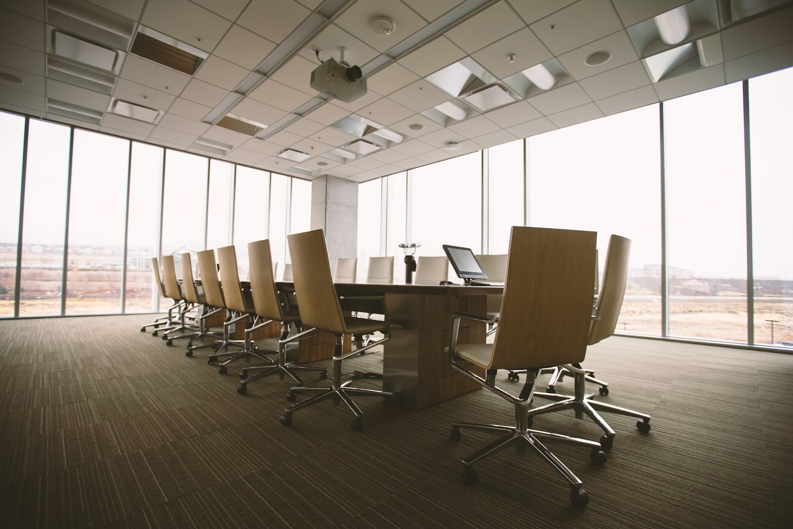 Oval brown wooden conference table and chairs inside a quiet conference room.
