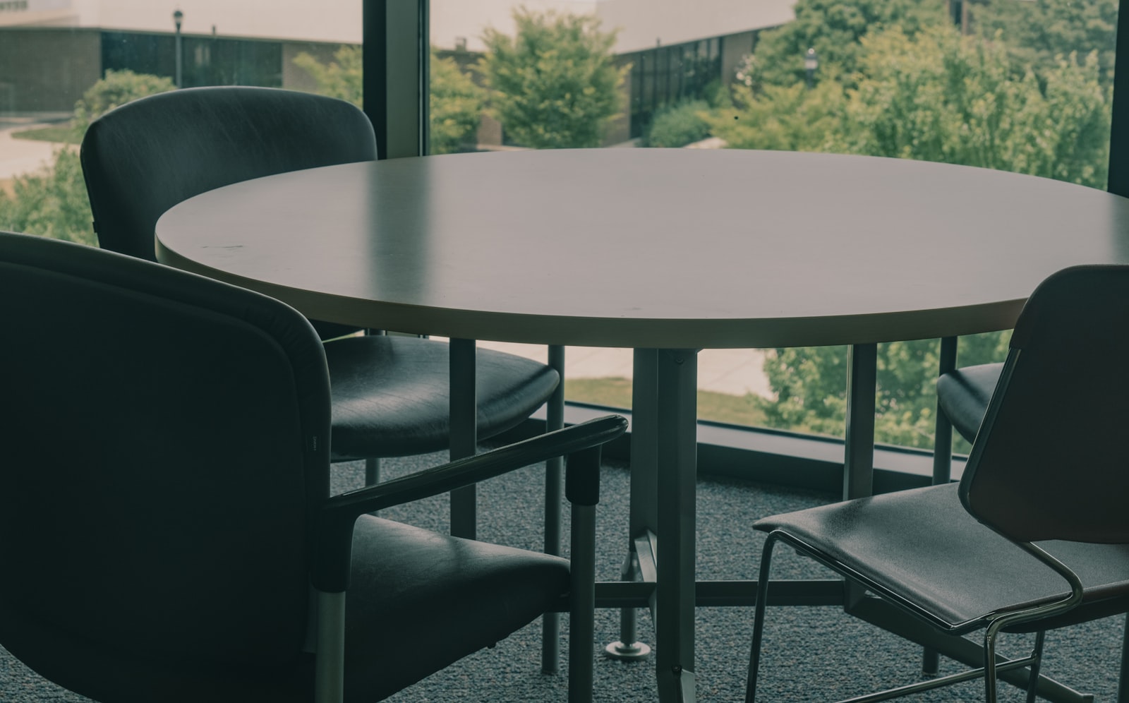 A table and chairs set in front of a large window with morning light.