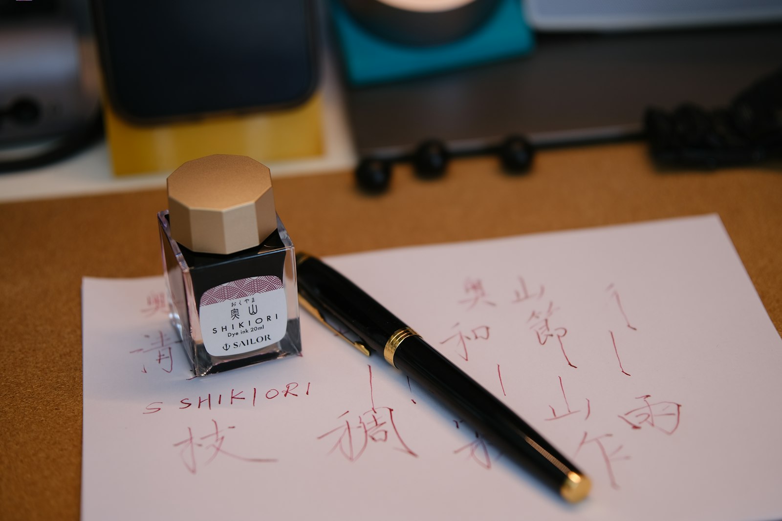 Fountain pen and ink bottle resting on a sheet of paper with handwriting.