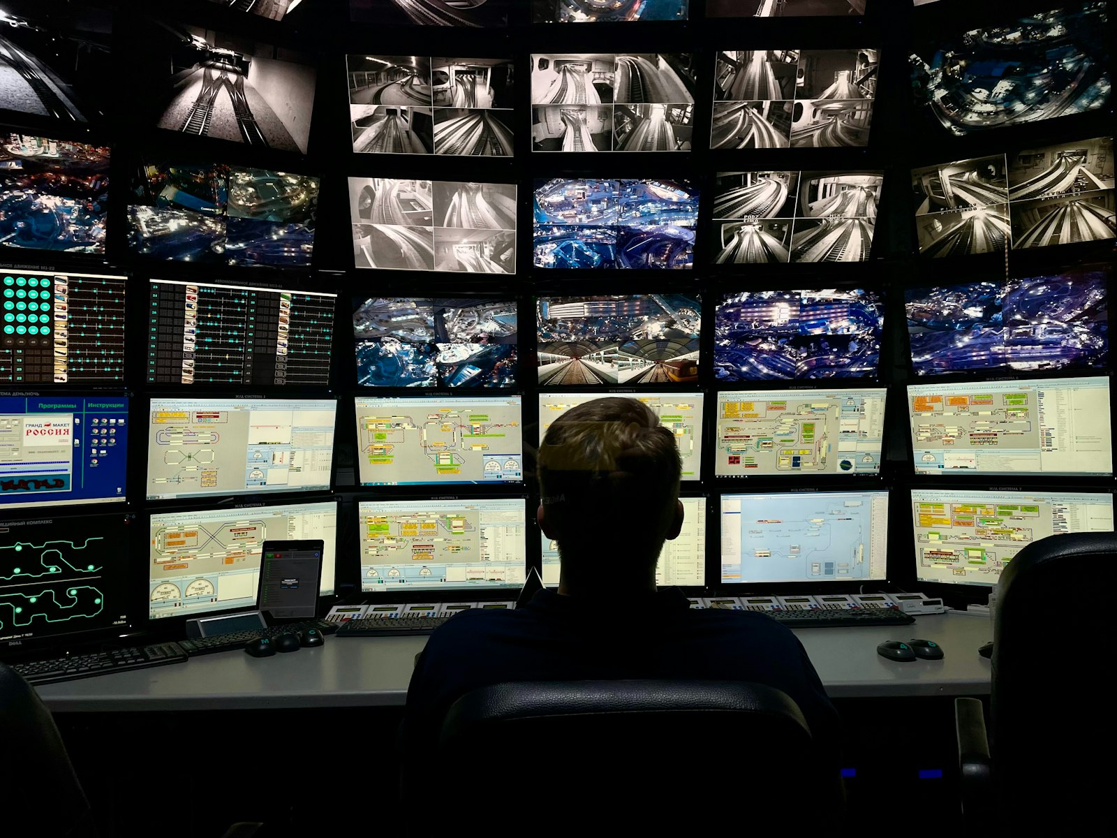 Dispatcher silhouetted at a desk against a wall of monitors at night