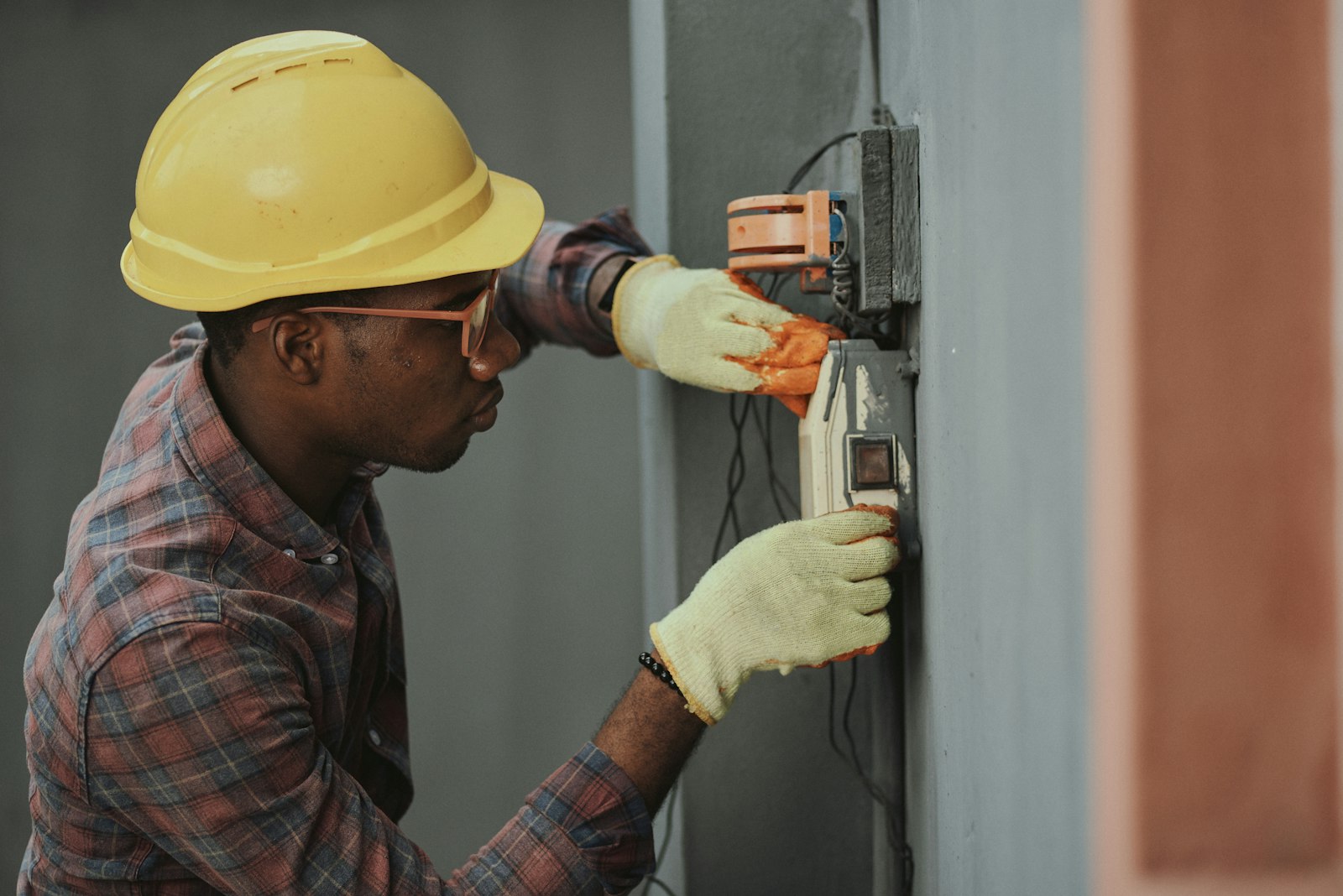 Field tech in a hardhat holding a power tool on a job site, mid-task
