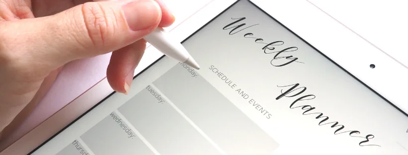 Set a schedule. A woman using a touch-pen to write in her weekly planner on an iPad.