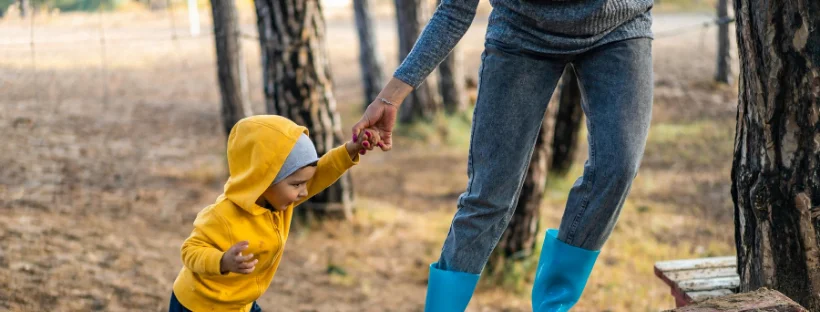 Ask for help Mom helping her kid walk in a public park.