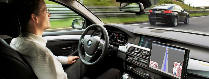 A person driving hands-free to work in a BMW. The inside of the dashboard are visible.
