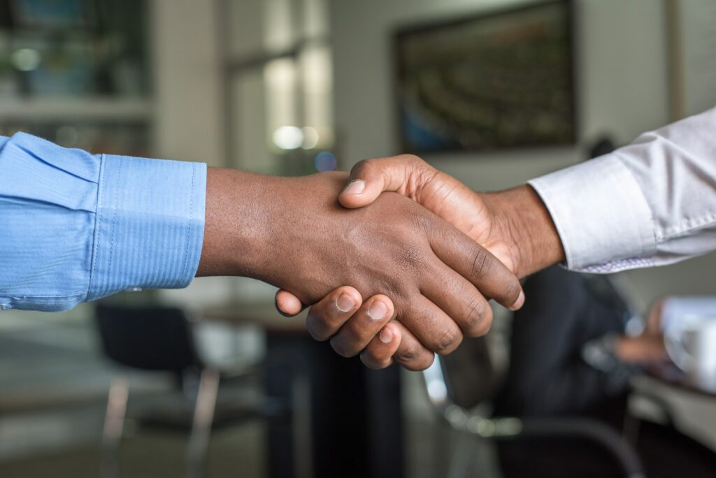 Close-up of two people in office attire shaking hands.