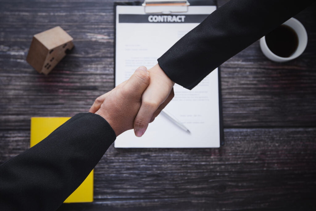 two people shaking hands over a contract