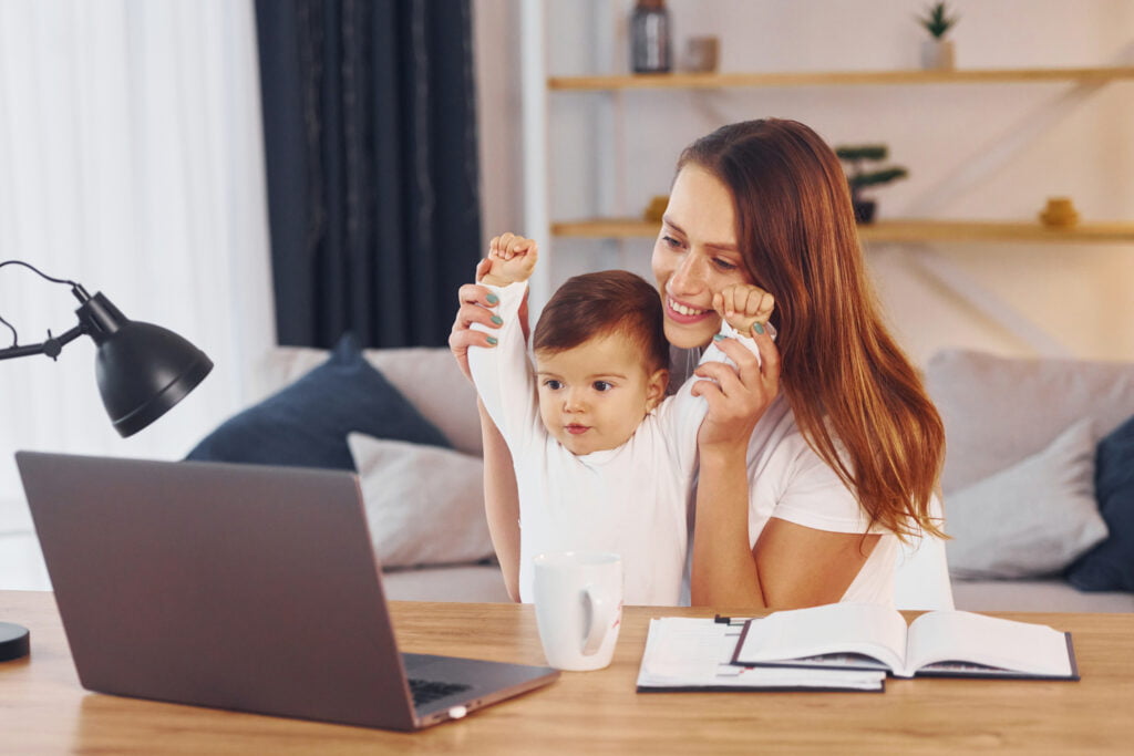 Mom working at home in front of laptop with her kid