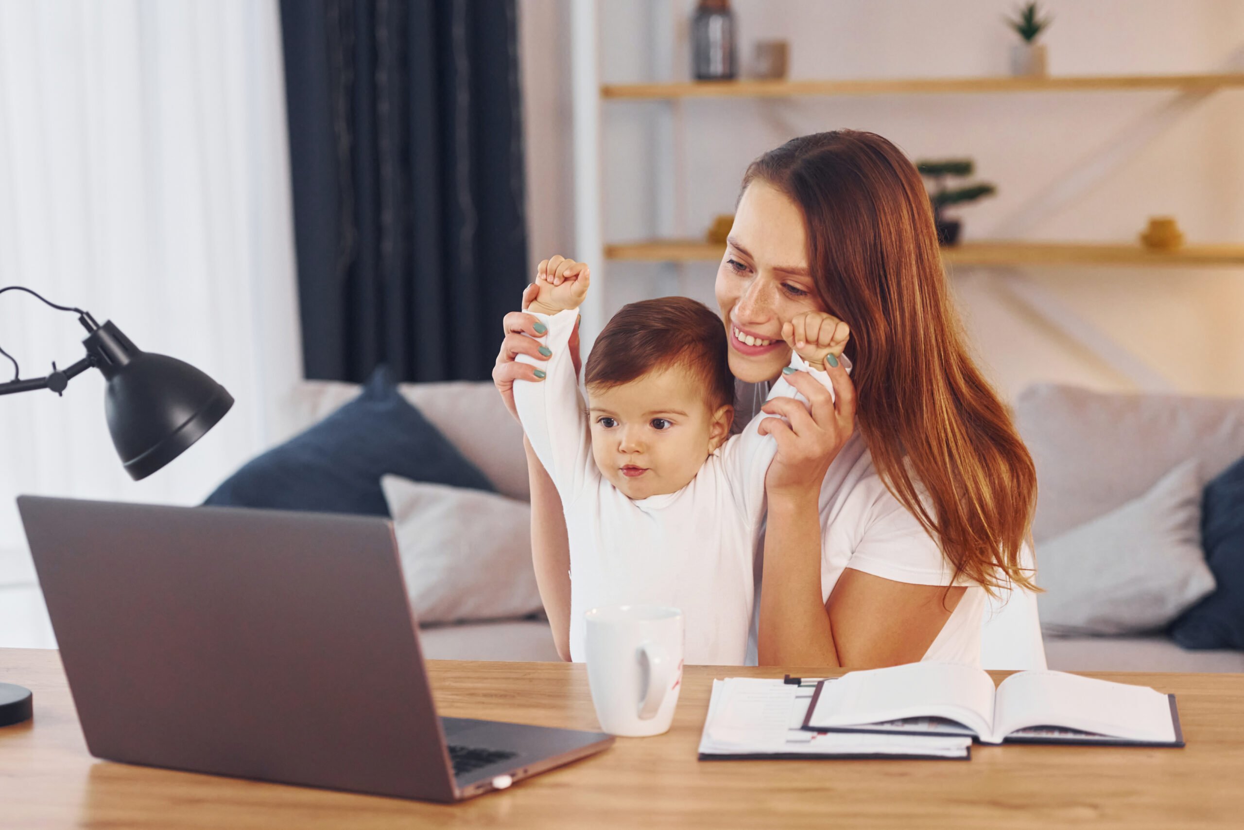 Mom working at home in front of laptop with her kid